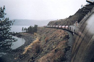 grain train and several cars travelling along beside water